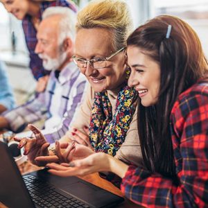 Young volunteers help senior people on the computer. Young people giving senior people introduction to internet